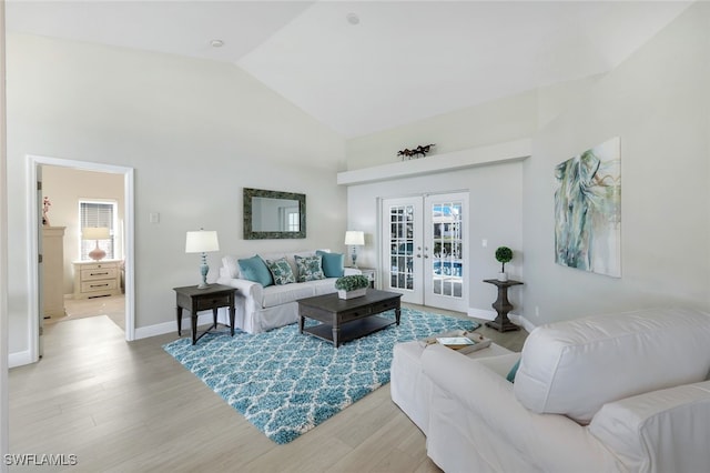 living room featuring light hardwood / wood-style flooring, high vaulted ceiling, and french doors