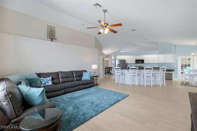 living room with lofted ceiling, ceiling fan with notable chandelier, and light hardwood / wood-style flooring