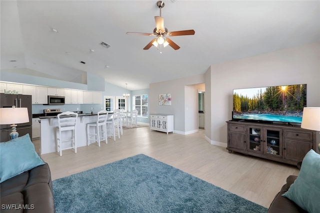 living room with lofted ceiling, ceiling fan with notable chandelier, and light wood-type flooring