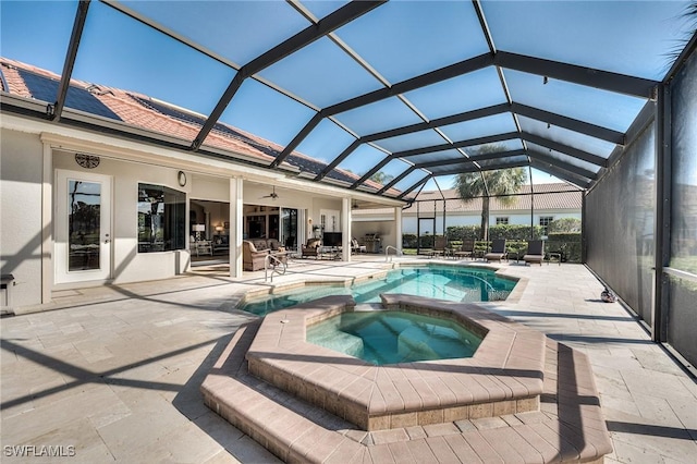 view of swimming pool with glass enclosure, a patio area, and an in ground hot tub