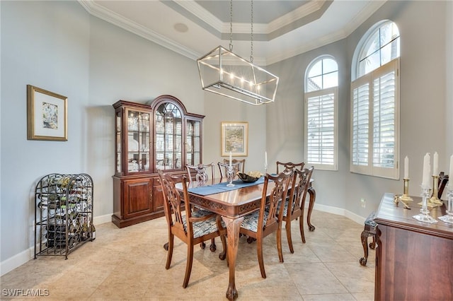 tiled dining room with plenty of natural light, ornamental molding, a raised ceiling, and a notable chandelier