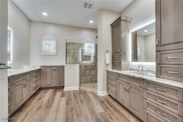 bathroom featuring a tile shower, wood-type flooring, and vanity