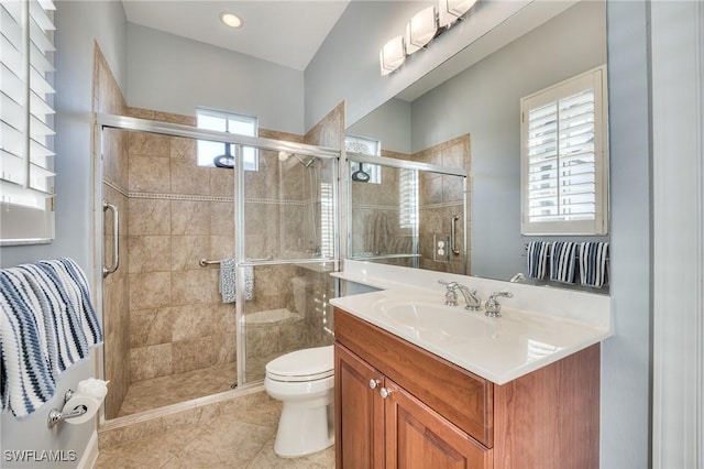 bathroom featuring toilet, a wealth of natural light, a shower with door, and vanity