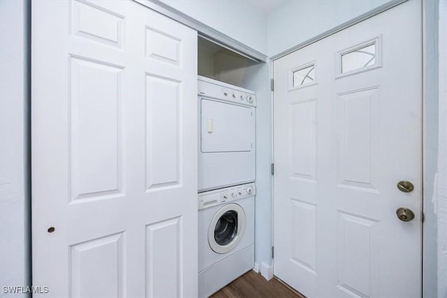 washroom featuring stacked washer / drying machine and dark wood-type flooring