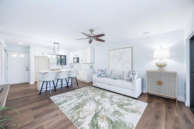 living room featuring dark wood-type flooring and ceiling fan