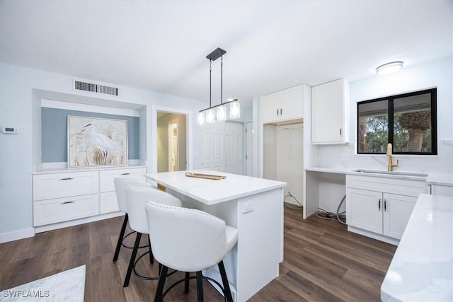 kitchen with white cabinetry, dark hardwood / wood-style floors, a center island, and pendant lighting