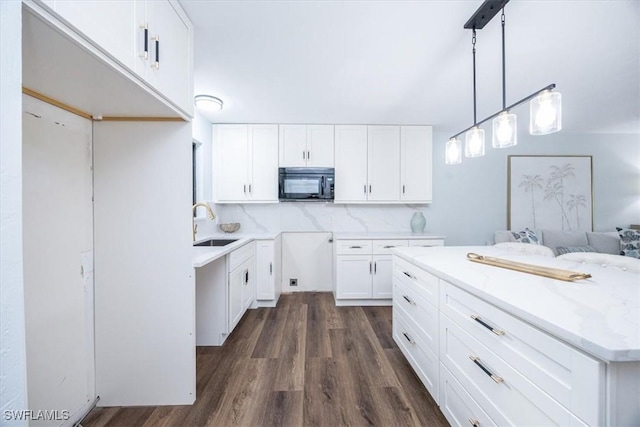 kitchen featuring pendant lighting, sink, dark hardwood / wood-style floors, white cabinets, and decorative backsplash