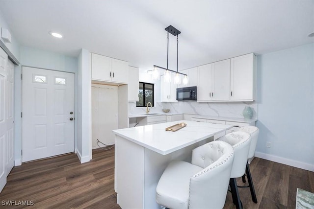 kitchen with sink, dark hardwood / wood-style floors, white cabinets, pendant lighting, and backsplash