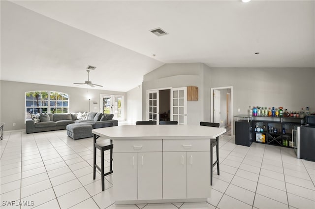 kitchen featuring white cabinetry, light tile patterned floors, a center island, and a kitchen bar