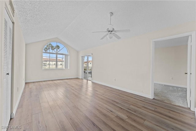 unfurnished living room featuring lofted ceiling, ceiling fan, a textured ceiling, and light hardwood / wood-style floors