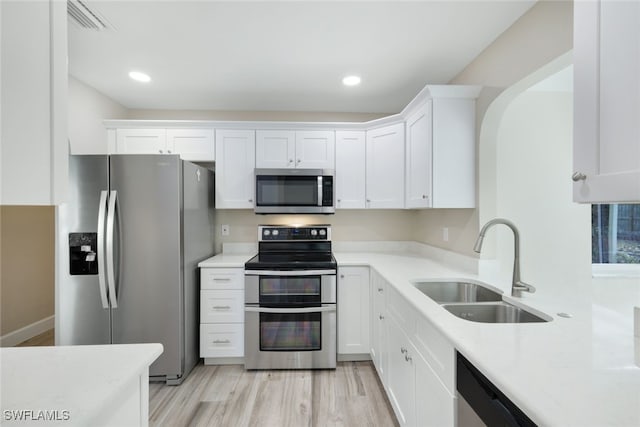 kitchen with light wood-type flooring, stainless steel appliances, white cabinetry, and sink