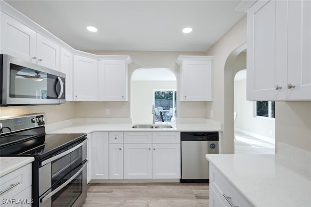 kitchen with light stone counters, sink, white cabinets, and appliances with stainless steel finishes