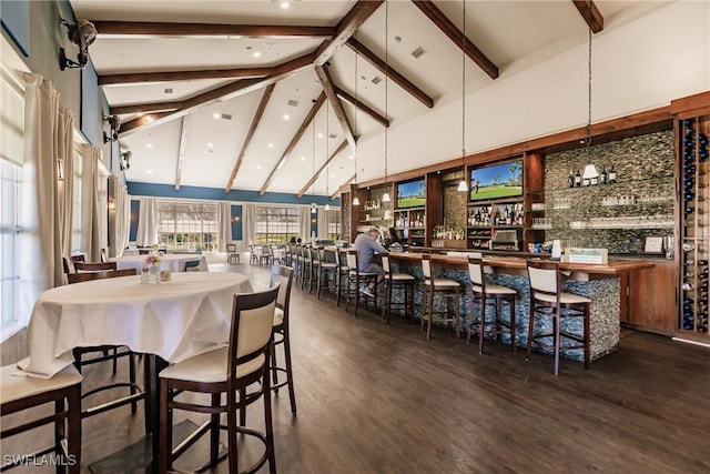 dining room featuring dark wood-type flooring, bar area, beam ceiling, and high vaulted ceiling