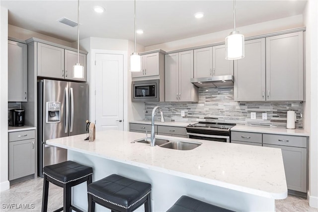 kitchen with sink, light stone counters, decorative light fixtures, gray cabinets, and stainless steel appliances