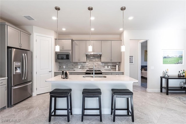 kitchen with gray cabinets, pendant lighting, sink, a kitchen island with sink, and stainless steel appliances