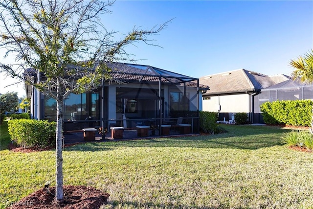 back of property with a yard and glass enclosure