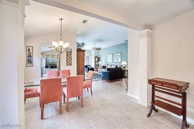 dining space with ceiling fan with notable chandelier, light tile patterned floors, and vaulted ceiling