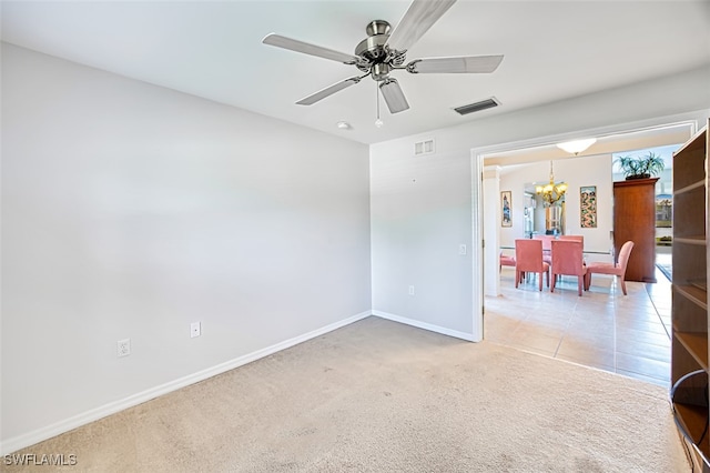 carpeted spare room with ceiling fan with notable chandelier