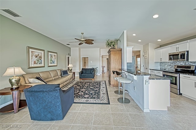 tiled living room with vaulted ceiling, ceiling fan, and sink