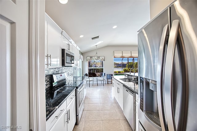 kitchen with lofted ceiling, sink, light tile patterned flooring, stainless steel appliances, and white cabinets