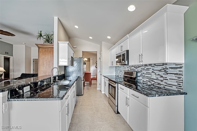 kitchen with white cabinets, stainless steel appliances, dark stone counters, sink, and light tile patterned floors