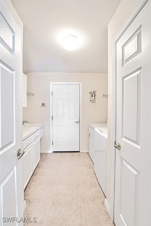 laundry room with light tile patterned floors, independent washer and dryer, and cabinets