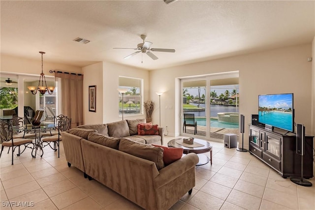 tiled living room with ceiling fan with notable chandelier