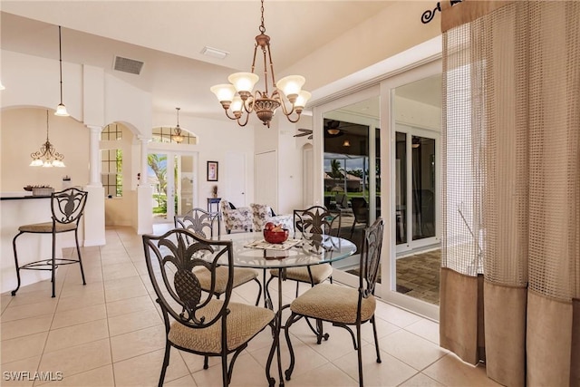 tiled dining room featuring an inviting chandelier and decorative columns