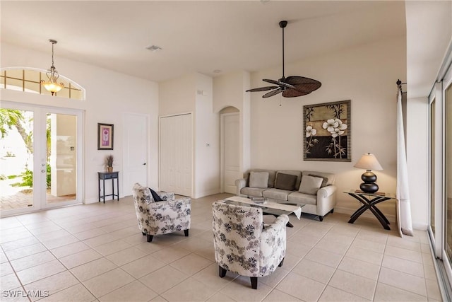 tiled living room with ceiling fan with notable chandelier