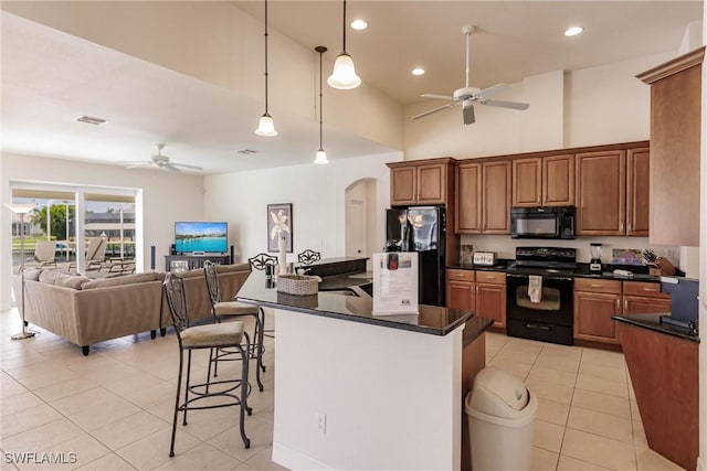 kitchen with pendant lighting, black appliances, ceiling fan, light tile patterned floors, and a breakfast bar area