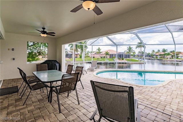 view of pool featuring glass enclosure, ceiling fan, a patio area, a grill, and a water view