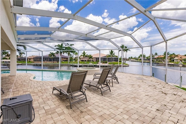 view of pool with a patio area, glass enclosure, a water view, and an in ground hot tub