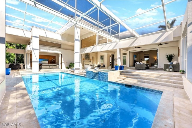 view of pool featuring glass enclosure, ceiling fan, a patio area, outdoor lounge area, and an in ground hot tub