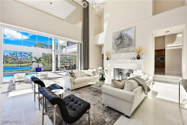 living room featuring a fireplace, a water view, and a high ceiling