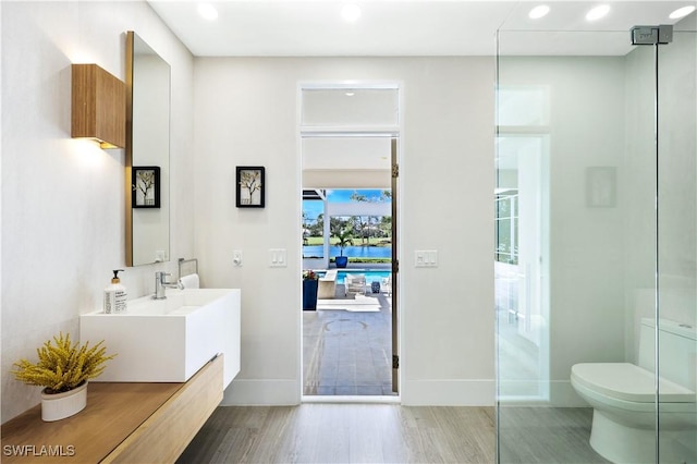 bathroom with hardwood / wood-style flooring, a shower, toilet, and vanity