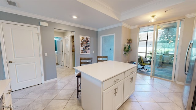 kitchen featuring white cabinetry, stainless steel fridge, ornamental molding, a kitchen island, and a breakfast bar