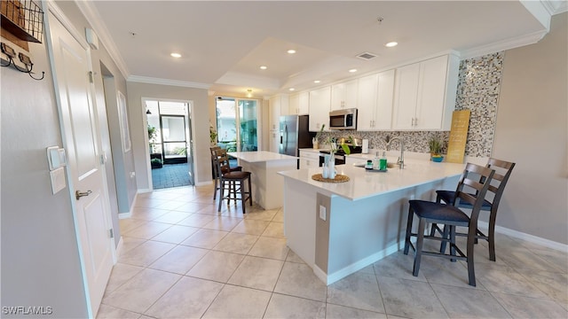 kitchen with white cabinets, appliances with stainless steel finishes, a kitchen bar, and kitchen peninsula