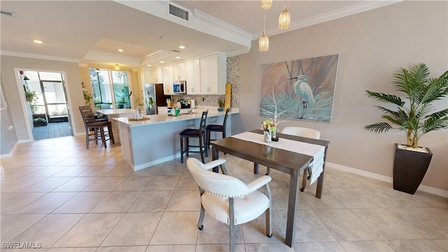 tiled dining space with a tray ceiling and crown molding