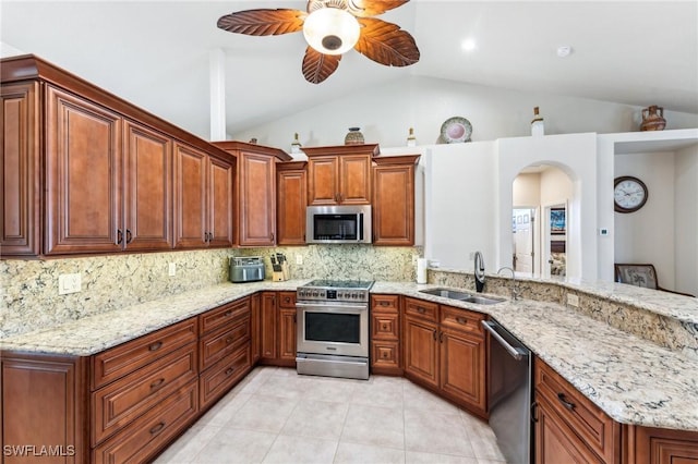 kitchen featuring sink, appliances with stainless steel finishes, tasteful backsplash, light stone countertops, and vaulted ceiling