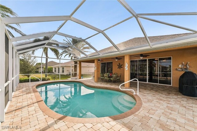 view of swimming pool featuring ceiling fan, a patio, and glass enclosure