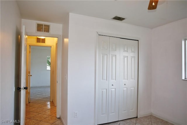 unfurnished bedroom with a closet, light tile patterned floors, and ceiling fan