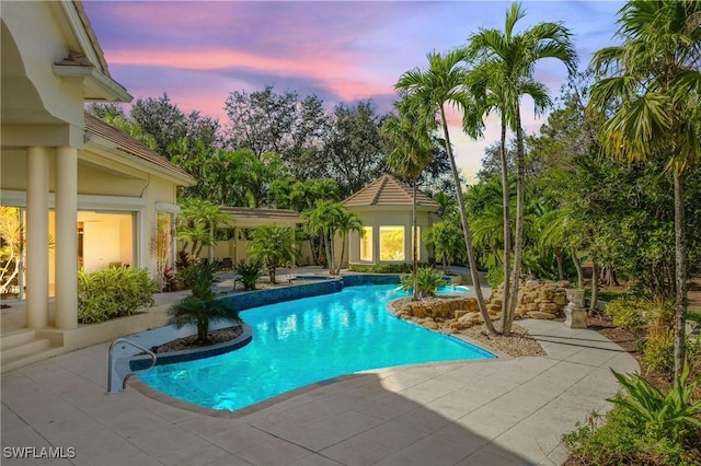 pool at dusk featuring an outbuilding and a patio