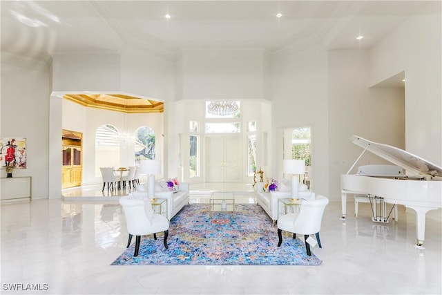 living room featuring a towering ceiling, plenty of natural light, and ornamental molding