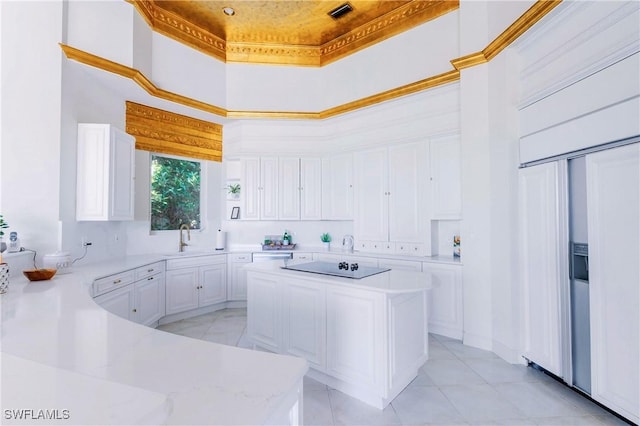 kitchen featuring kitchen peninsula, a towering ceiling, sink, crown molding, and white cabinetry