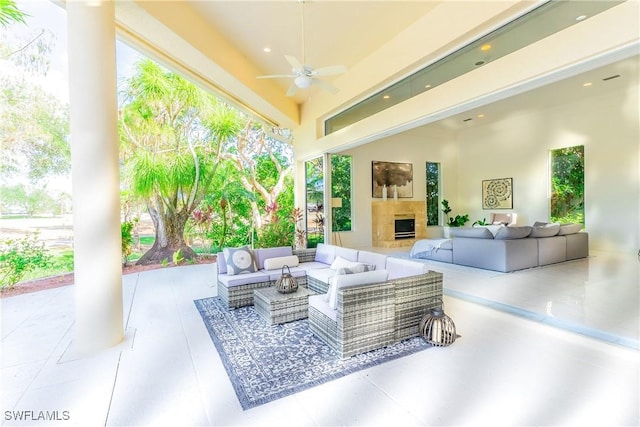 view of patio / terrace with ceiling fan and an outdoor living space with a fireplace