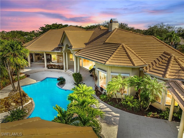 pool at dusk featuring a patio area