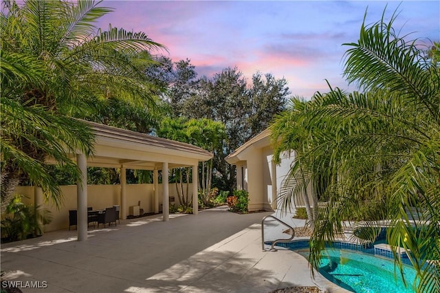 pool at dusk featuring a gazebo and a patio