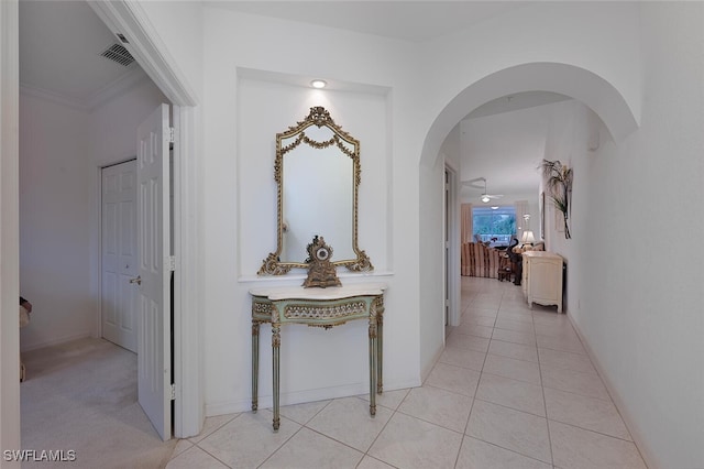 hallway with light tile patterned flooring and crown molding