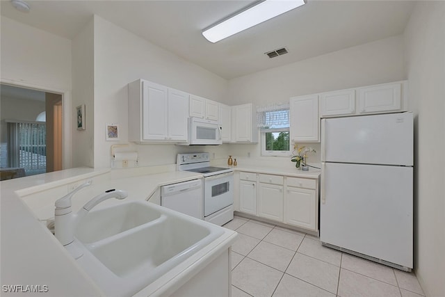 kitchen with light tile patterned floors, white appliances, sink, white cabinetry, and kitchen peninsula