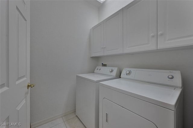 washroom featuring cabinets, light tile patterned floors, and washing machine and clothes dryer